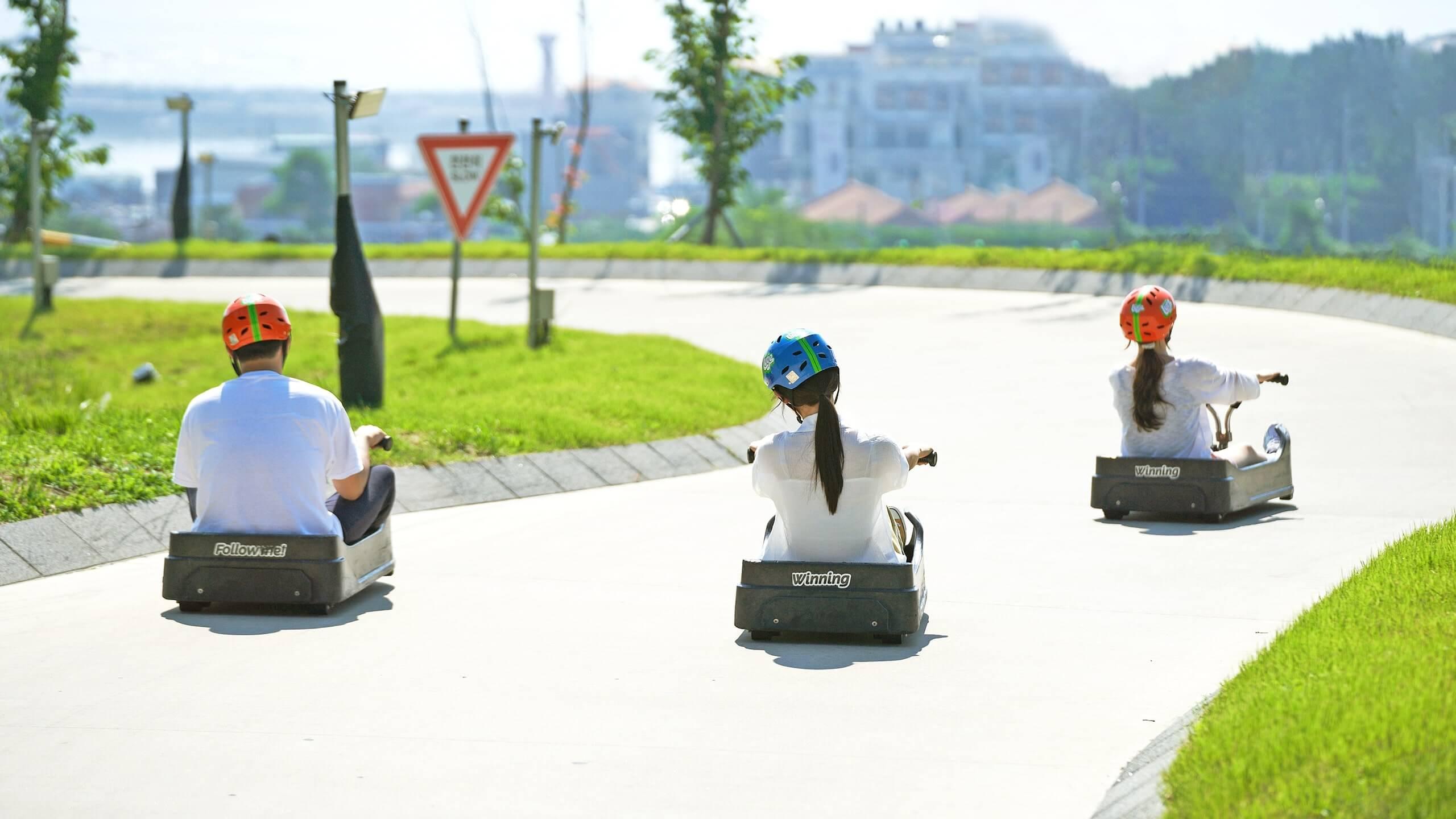 Three people race down the Luge tracks at Skyline Luge busan.