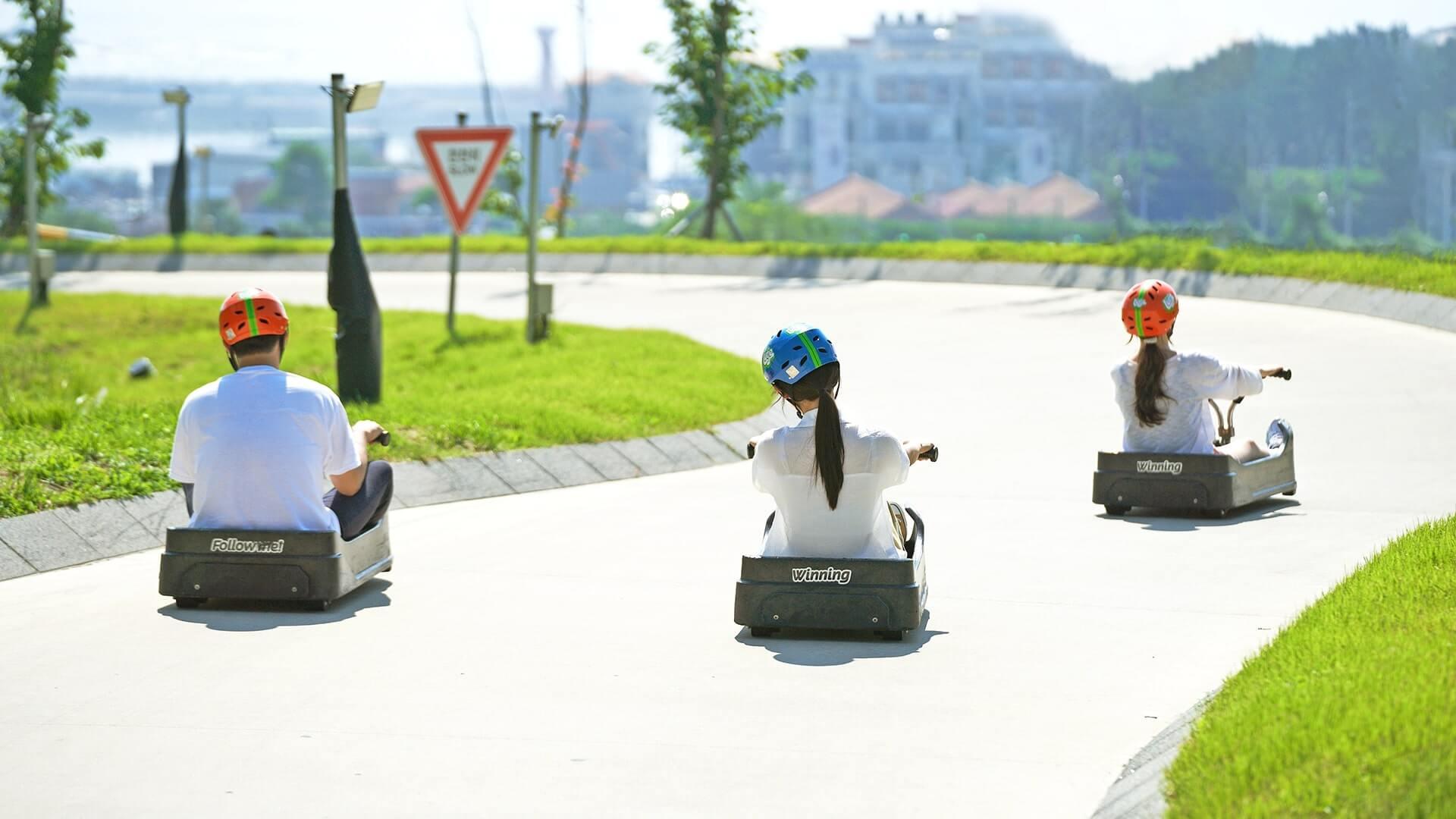 Three people race down the Luge tracks at Skyline Luge Busan.