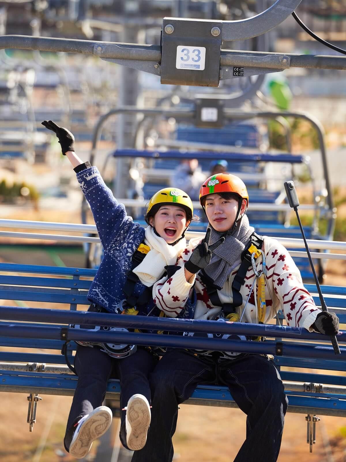 A couple poses for a photo on the Skyline Luge Busan chairlift.