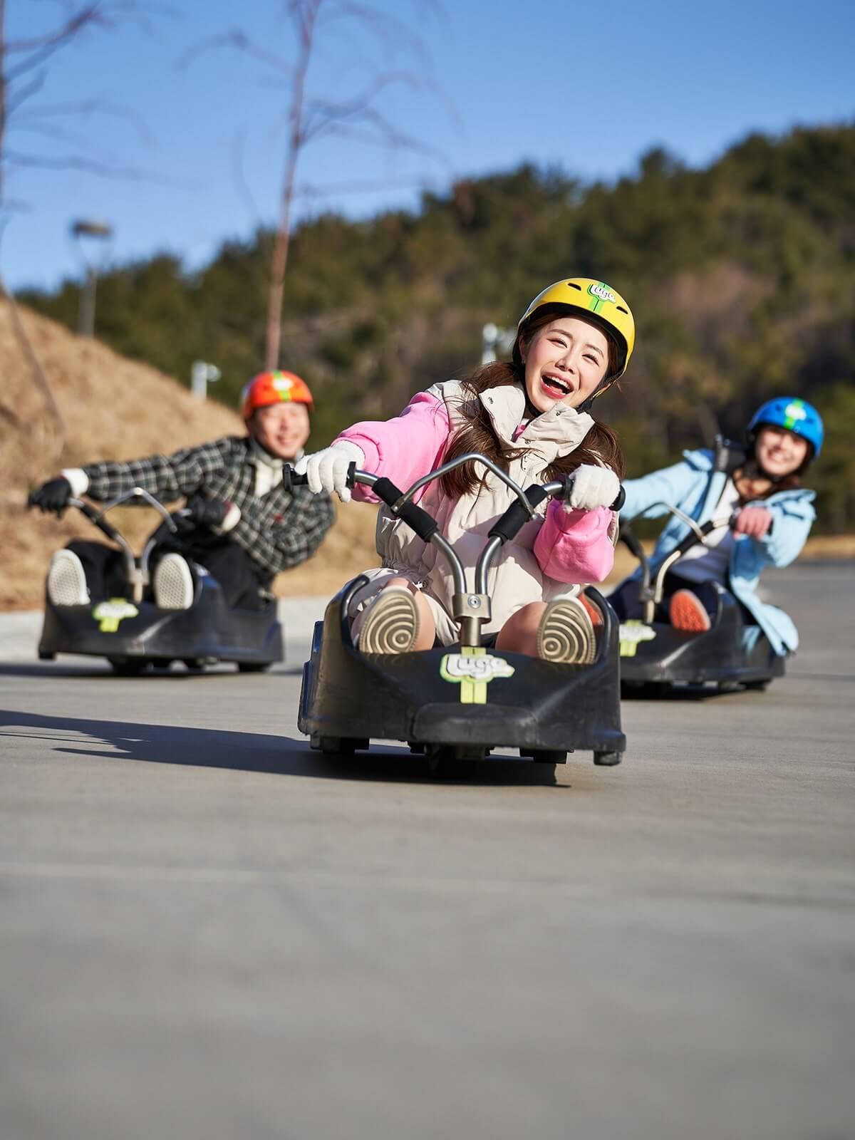 A group of people smile as they ride around a corner on the Luge.
