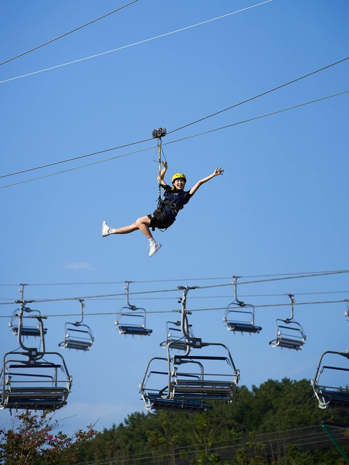 A lady poses with her hand out mid way down the Hyfly zipline at Skyline Luge Busan.