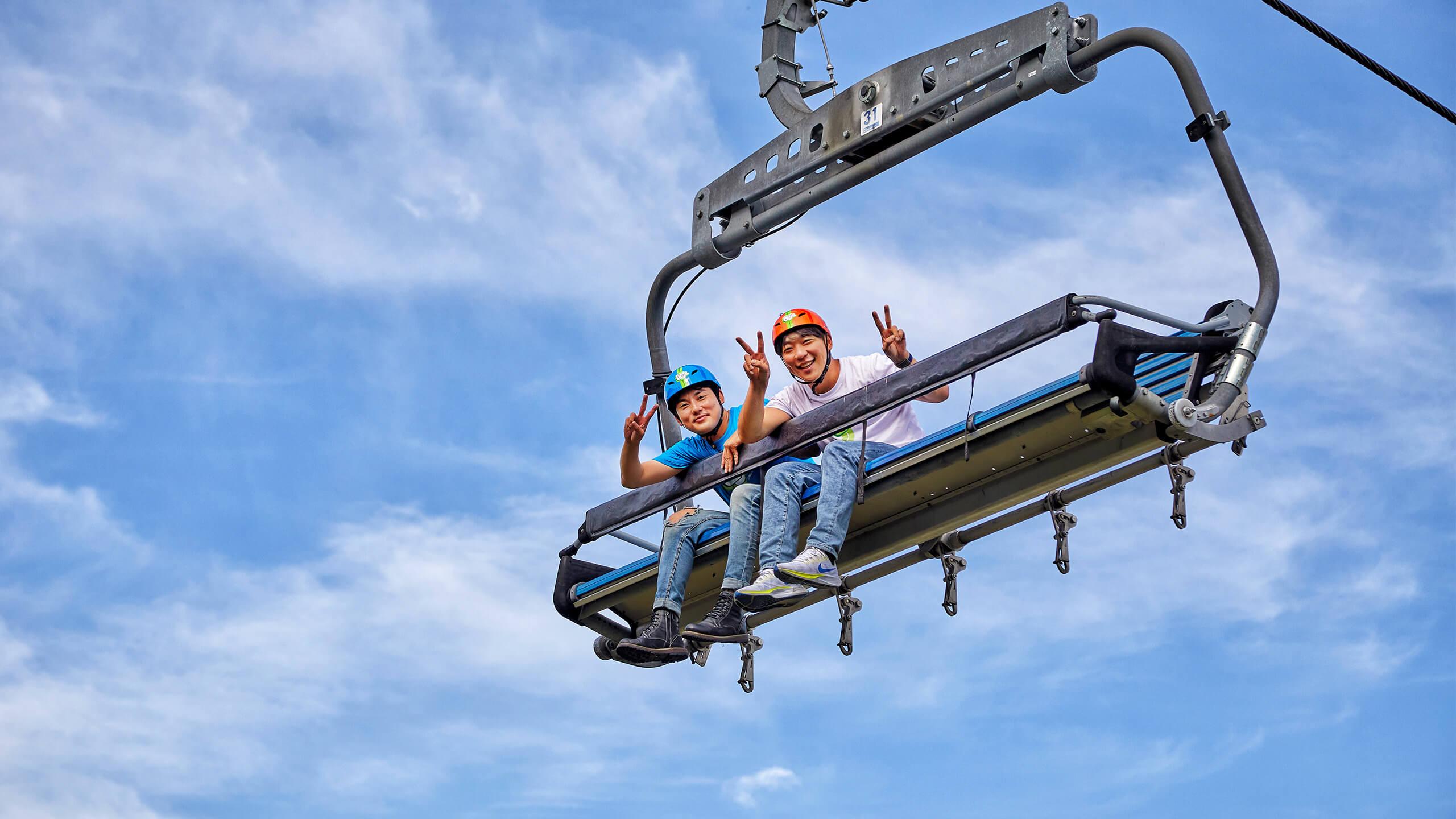 Two friends pull the peace sign whilst riding the Chairlift at Skyline Luge Tongyeong.