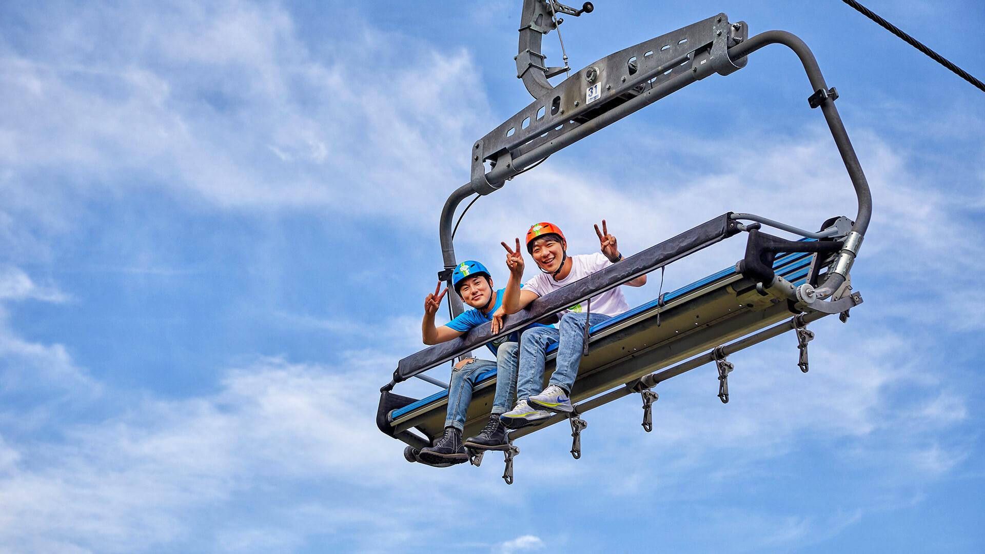Two friends pull the peace sign whilst riding the Chairlift at Skyline Luge Tongyeong.