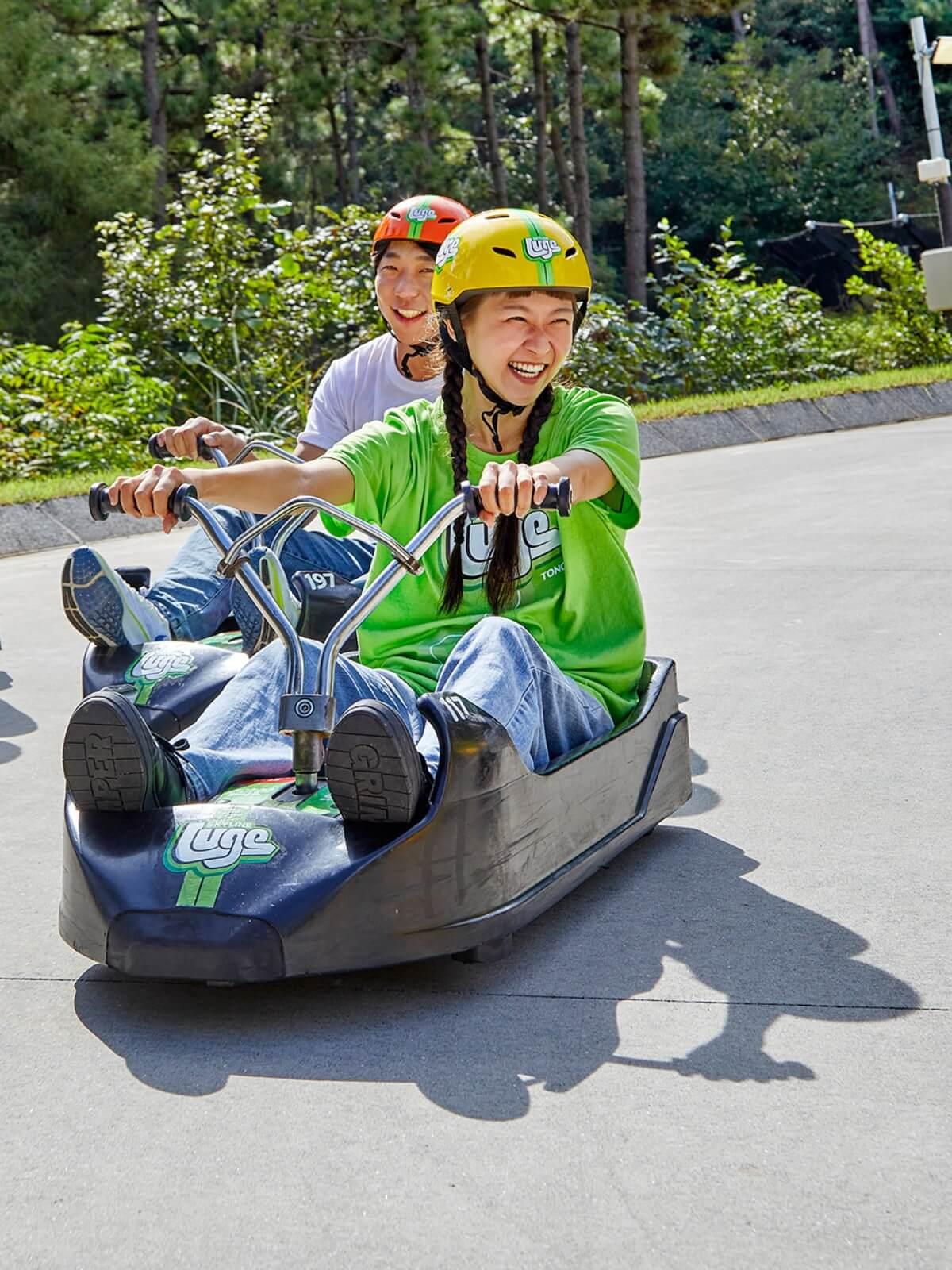 A lady smiles widely as she leads the race down the Luge tracks at Skyline Luge Tongyeong.
